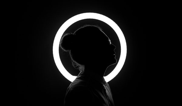 Person im Dunkeln vor einem Runden Licht